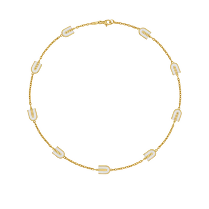 Gold necklace with white geometric pendants on a white background
